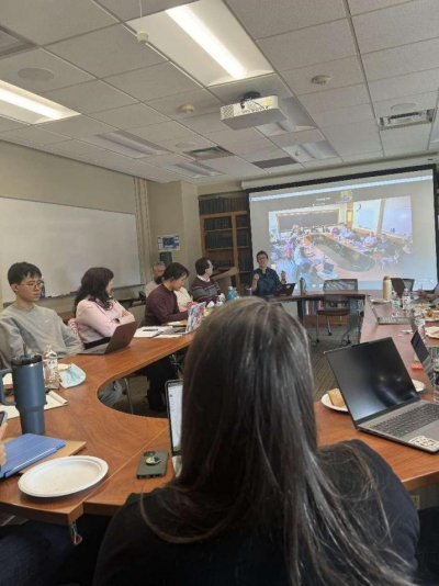 group discussion at seminar table with zoom screen in background