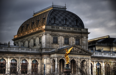 Old European building with golden statue in front and gold/silver domed roof.